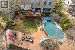 Rear exterior featuring a multi-level wood deck, an irregular-shaped inground pool, a gazebo, and a manicured lawn - 