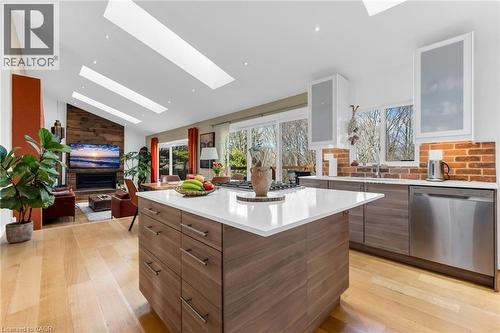 Open-concept living space featuring a central kitchen island with a white countertop, light wood-finish flooring, and a brick-finish backsplash - 39 Hilts Drive, Stoney Creek, ON - Indoor Photo Showing Kitchen With Upgraded Kitchen