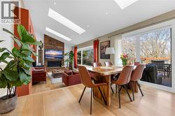 Vaulted ceilings with multiple skylights, light wood-finish flooring, and a natural wood accent wall featuring a built-in fireplace - 