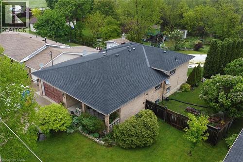 Brick exterior residence featuring a dark shingle roof, attached garage with a wood-panel door, and a covered front porch - 64 Winnett Street N, Cayuga, ON 
