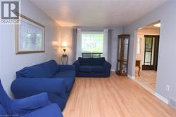 Living area featuring wood-finish flooring, light grey walls, and a large window with white trim - 