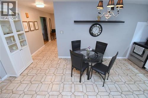 Neutral-toned geometric tile flooring extends throughout this space, featuring a kitchen area with stainless steel appliances and a white built-in display cabinet - 64 Winnett Street N, Cayuga, ON 