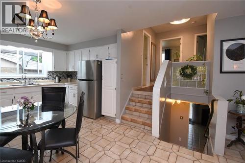 Bright kitchen featuring white cabinetry, stainless steel refrigerator, and a mosaic tile backsplash - 64 Winnett Street N, Cayuga, ON 
