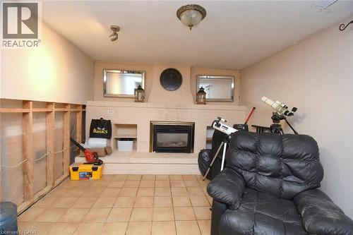 Interior room featuring a fireplace with a raised hearth, recessed shelving, and a tiled floor - 64 Winnett Street N, Cayuga, ON 