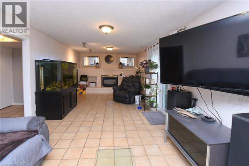 Spacious interior featuring neutral tone tile flooring, a fireplace with a light-colored mantel, and multiple ceiling-mounted light fixtures - 64 Winnett Street N, Cayuga, ON 