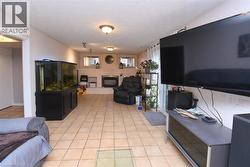 Spacious interior featuring neutral tone tile flooring, a fireplace with a light-colored mantel, and multiple ceiling-mounted light fixtures - 