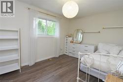 Bright room featuring wood-finish flooring and a single window with exterior tree scenery - 