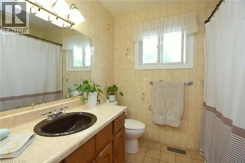 Bathroom featuring a wood-finish vanity with an oval sink, an overhead light fixture, and a large wall-mounted mirror - 64 Winnett Street N, Cayuga, ON 