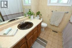 Bathroom featuring a single-basin vanity with a light-toned countertop, wood cabinetry, and a dark oval sink - 