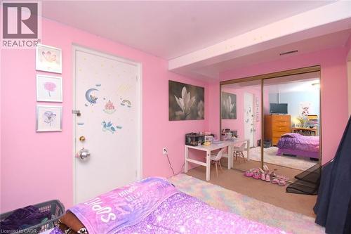Carpeted room featuring a full-wall mirrored closet, a white interior door, and light pink walls - 64 Winnett Street N, Cayuga, ON 