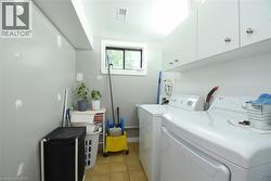 Laundry area featuring a window, tile flooring, and white wall cabinetry - 