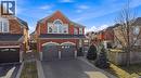 Brick and stone facade residence featuring an arched window, a two-car garage with arched accents, a covered front porch, and a paved driveway - 2070 Willhaven Trail, Oakville, ON  - Outdoor 