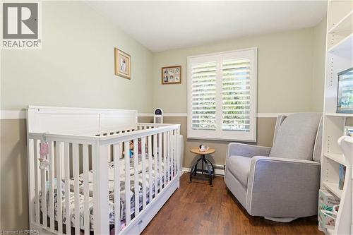Interior room featuring wood-finish flooring, two-tone wall paint, and a window with white plantation shutters - 26 Coachwood Road Unit# 6, Brantford, ON - Indoor Photo Showing Bedroom