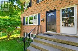 Brick exterior featuring a black paneled door with an arched window, white-framed windows, and black louvered shutters - 