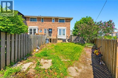 Brick exterior featuring white-framed windows, a rear entry door, and exterior stairs - 26 Coachwood Road Unit# 6, Brantford, ON - Outdoor