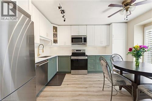 Modern kitchen featuring two-tone cabinetry, stainless steel appliances, and wood-finish flooring - 26 Coachwood Road Unit# 6, Brantford, ON - Indoor Photo Showing Kitchen