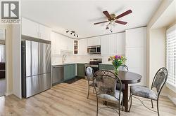 Kitchen featuring light wood-finish flooring, white upper cabinetry, and contrasting green lower cabinetry - 