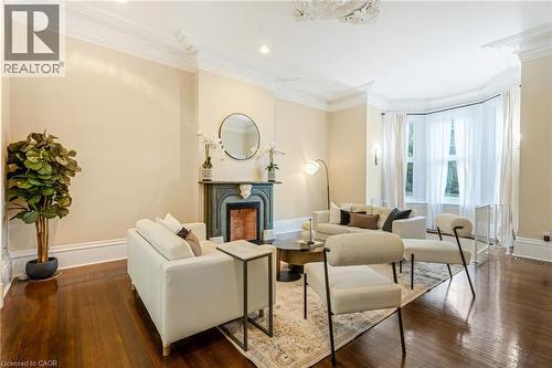 Sitting room with a premium fireplace, ornamental molding, dark wood-style floors, and recessed lighting - 46 Herkimer Street Unit# 2, Hamilton, ON - Indoor Photo Showing Living Room With Fireplace