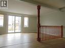 Light wood-finish flooring throughout, featuring a sliding glass door with two flanking windows, crown molding, and a warm wood baluster and railing system - 90 Bridlewreath Street Unit# Upper Unit, Kitchener, ON  - Indoor Photo Showing Other Room 