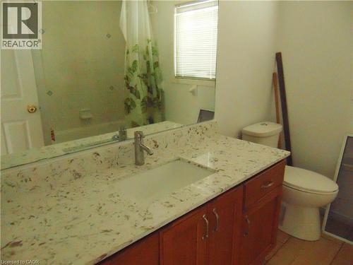 Bathroom vanity featuring a light-toned countertop with integrated sink, wood-finish cabinetry, and a chrome-finish faucet - 90 Bridlewreath Street Unit# Upper Unit, Kitchener, ON - Indoor Photo Showing Bathroom