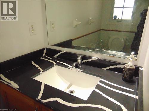Modern vanity featuring a black countertop with white veining, an integrated rectangular sink, a chrome single-handle faucet, and wood-finish cabinetry - 90 Bridlewreath Street Unit# Upper Unit, Kitchener, ON - Indoor