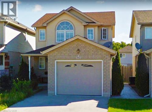 Two-story residence featuring a brick and siding exterior, an arched window, and an attached garage with a paved driveway - 90 Bridlewreath Street Unit# Upper Unit, Kitchener, ON - Outdoor