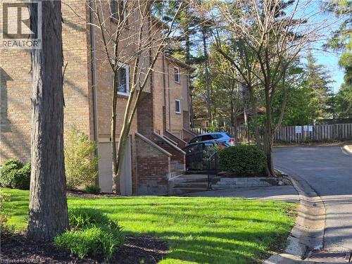 Brick exterior with white-framed windows, mature trees, and a manicured lawn - 95 Fonthill Road Unit# 2, Hamilton, ON - Outdoor