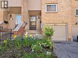 Brick facade townhome with an attached garage, a paved driveway, and a welcoming front entrance with an ornamental railing - 