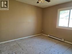 Room featuring a window with white trim, tan painted walls, and a ceiling fan with light fixture - 