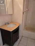 Bathroom featuring a dark wood-finish vanity with a light-colored countertop, an integrated sink, and a two-handle chrome faucet - 