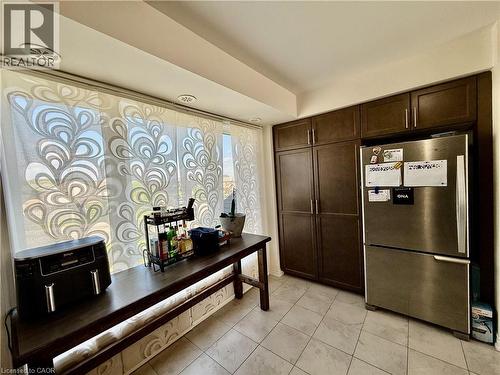 Kitchen area featuring wood-finish cabinetry, a stainless steel refrigerator, and tiled flooring - 146 Watson Parkway, Guelph, ON - Indoor