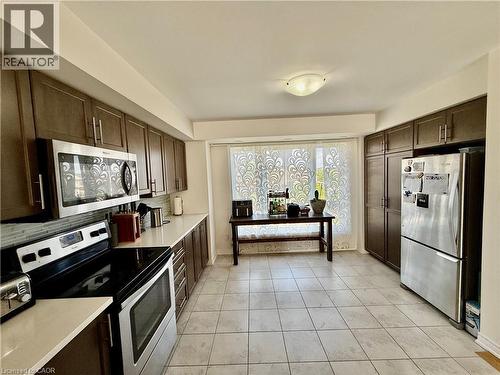 Kitchen featuring tile flooring, dark wood-finish cabinetry, light countertops, and stainless steel appliances - 146 Watson Parkway, Guelph, ON - Indoor Photo Showing Kitchen