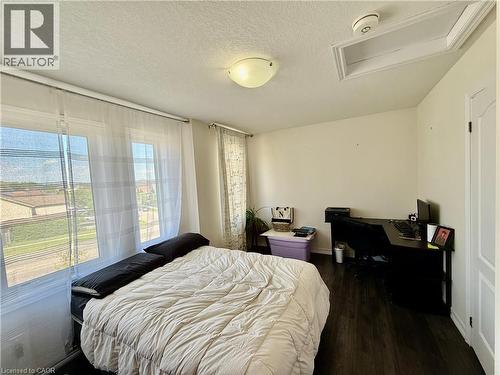 Spacious room featuring multiple windows, dark wood-finish flooring, a flush-mount ceiling light fixture, and a white paneled interior door - 146 Watson Parkway, Guelph, ON - Indoor Photo Showing Bedroom