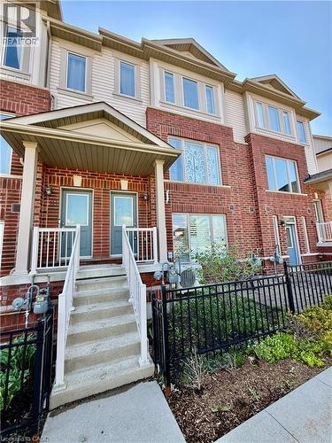 Townhouse exterior featuring brick and siding construction, covered front entrance, concrete steps with white railings, and a fenced front yard with plantings - 146 Watson Parkway, Guelph, ON - Outdoor