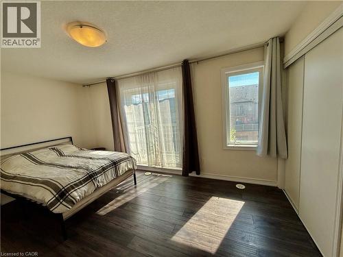 Bedroom featuring dark wood-finish flooring, white walls, and a sliding glass door to a balcony - 146 Watson Parkway, Guelph, ON - Indoor Photo Showing Bedroom