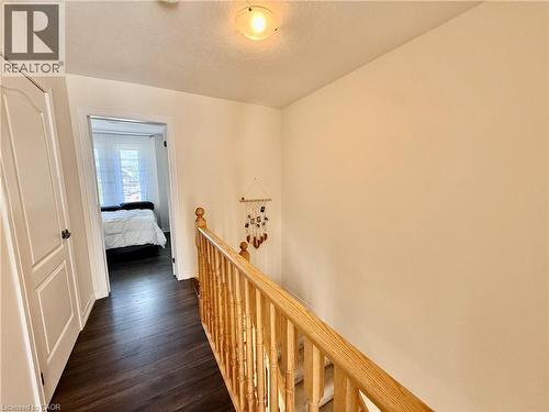 Hallway with dark wood-finish flooring, light-toned walls, and a natural wood railing - 146 Watson Parkway, Guelph, ON - Indoor Photo Showing Other Room
