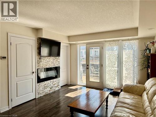 Living area featuring wood-finish flooring, a contemporary fireplace with a stacked stone facade, and direct access to an outdoor space through glass patio doors - 146 Watson Parkway, Guelph, ON - Indoor Photo Showing Living Room With Fireplace