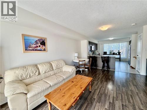 Open-concept living area featuring wood-finish flooring, a kitchen island with seating, dark wood cabinetry, and stainless steel appliances - 146 Watson Parkway, Guelph, ON - Indoor Photo Showing Living Room