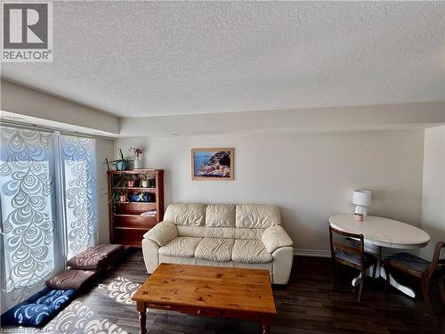 Living area featuring wood-finish flooring, light-toned walls, and a textured ceiling - 146 Watson Parkway, Guelph, ON - Indoor Photo Showing Living Room