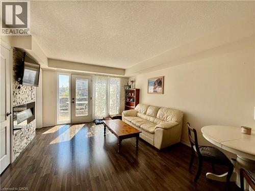 Living area featuring wood-finish flooring, a contemporary fireplace with a stacked stone facade, and double patio doors - 146 Watson Parkway, Guelph, ON - Indoor Photo Showing Living Room