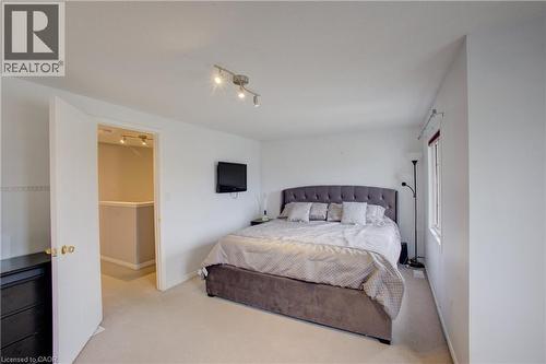 Carpeted room featuring a window with a valance, a ceiling-mounted track light fixture, and a white interior door with brass hardware - 53 Prosperity Drive, Kitchener, ON - Indoor Photo Showing Bedroom