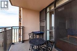 Outdoor balcony featuring a painted concrete floor, black metal railings, and a full-height sliding glass door - 