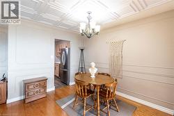 Dining area featuring a coffered ceiling, hardwood flooring, and decorative wall molding - 