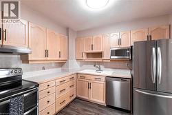 Kitchen featuring light wood cabinetry with dark hardware, stainless steel appliances, a light-toned countertop, and tile backsplash - 