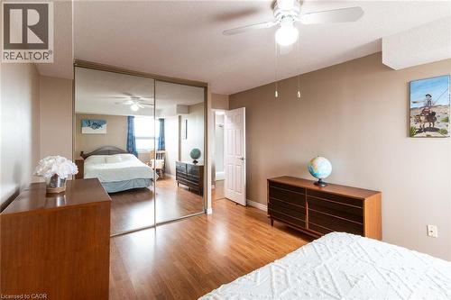 Bedroom featuring wood-finish flooring, a ceiling fan with integrated lighting, and a full-wall mirrored closet - 500 Green Road Unit# 901, Stoney Creek, ON - Indoor Photo Showing Bedroom