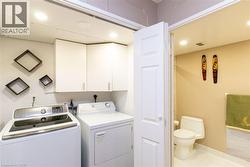 Dedicated laundry area featuring white upper cabinetry, recessed lighting, and white appliances - 
