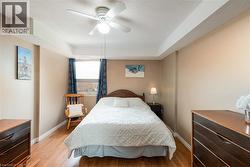 Interior room featuring wood-finish flooring, a ceiling fan with integrated lighting, and a window with dark blue drapes - 
