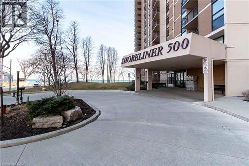 Building exterior featuring a covered portico entry with ""SHORELINER 500"" signage, a paved driveway, and visible water in the background - 500 Green Road Unit# 901, Stoney Creek, ON - Outdoor