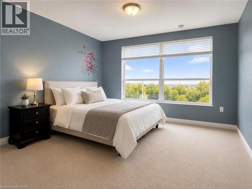 Expansive window featuring a broad exterior outlook, accompanied by neutral carpeting, a semi-flush ceiling light fixture, and light blue wall tones - 255 Keats Way Unit# 606, Waterloo, ON - Indoor Photo Showing Bedroom
