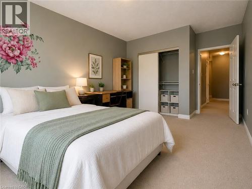 Bedroom featuring plush carpet flooring, a built-in closet with sliding doors and interior shelving, a desk area with wood-finish shelving, and a white six-panel door - 255 Keats Way Unit# 606, Waterloo, ON - Indoor Photo Showing Bedroom